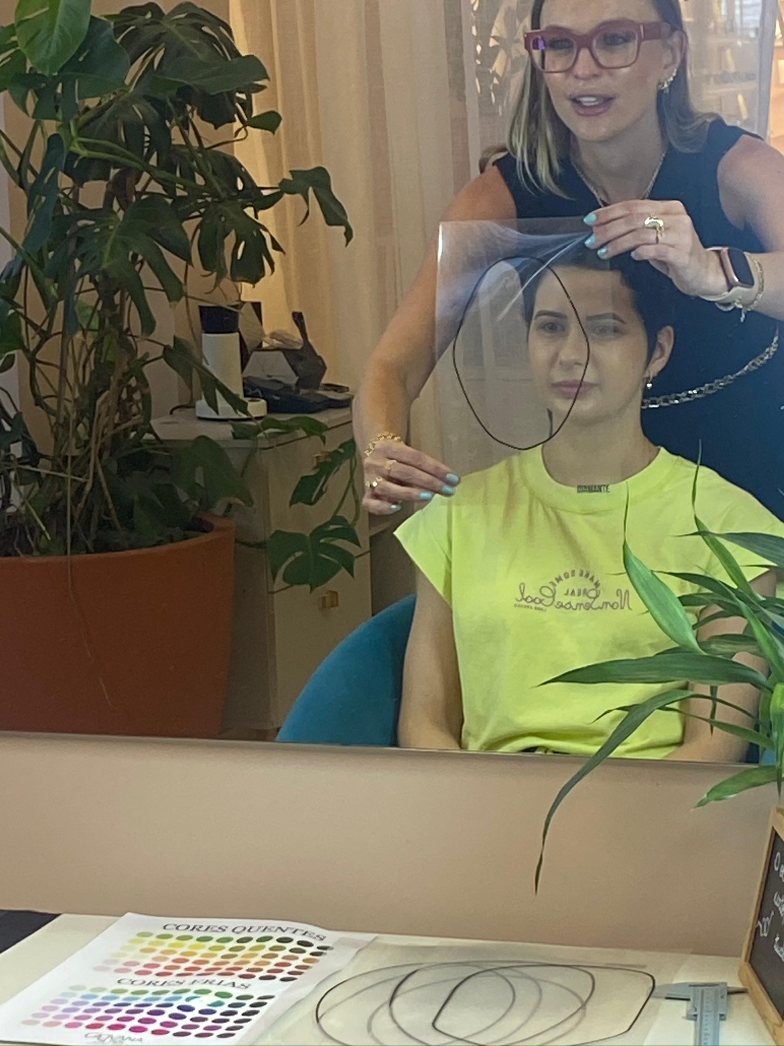 Giovana Suss analisando o formato do rosto de uma cliente com um molde de visagismo