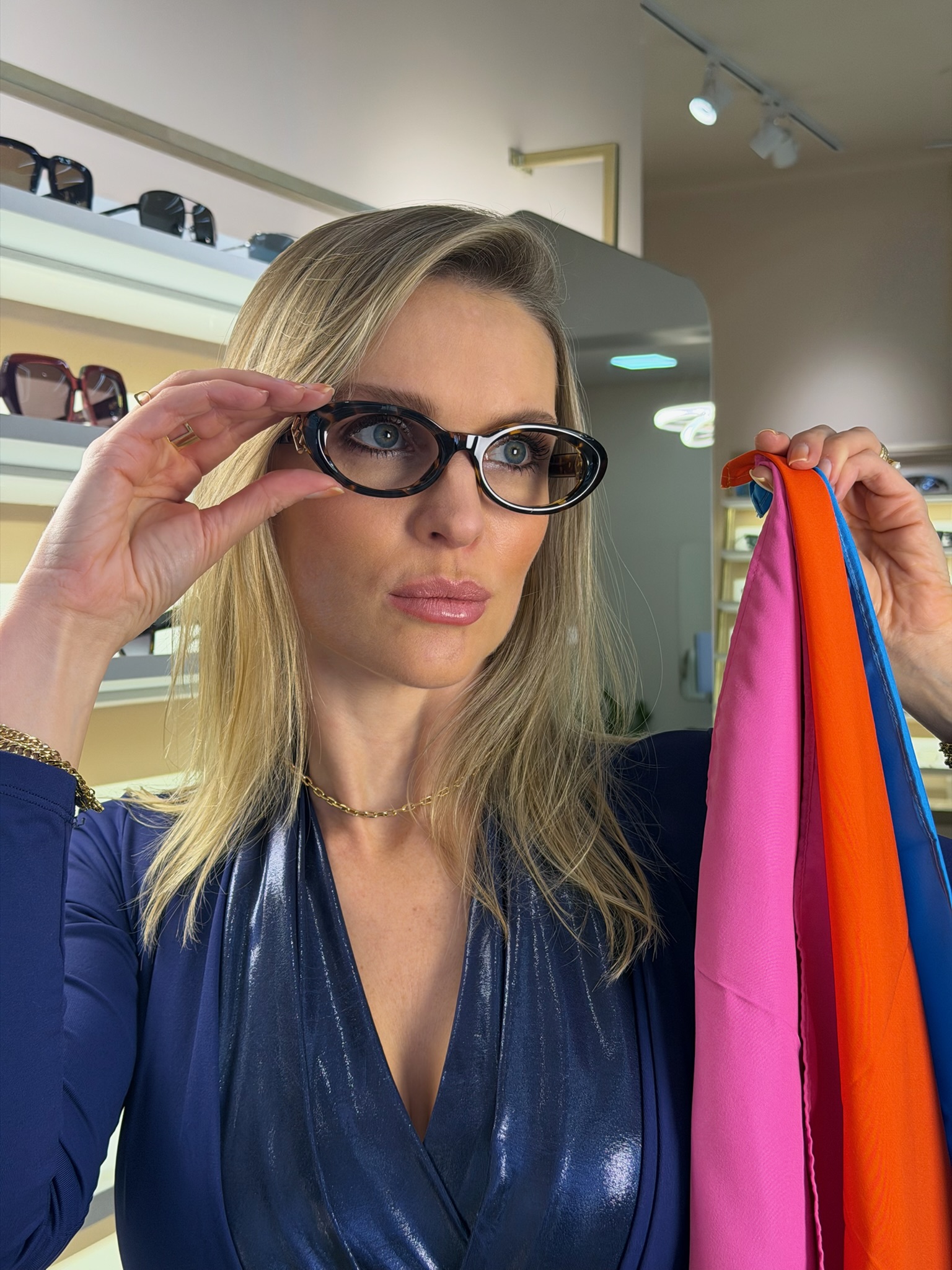 Giovana Suss ajustando os óculos e segurando tecidos coloridos para análise de coloração